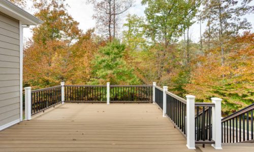 Patio Handrails Stairs1 A spacious wooden deck attached to a house, bordered by a simple railing and overlooking a vibrant autumn forest, capturing the essence of tranquility and nature's beauty.